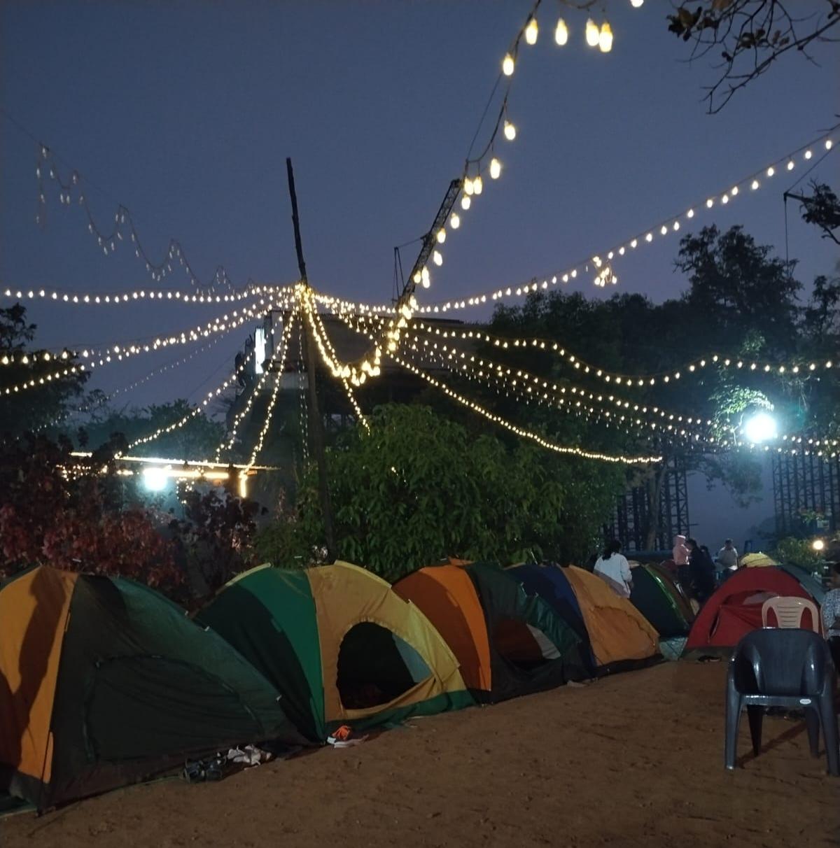 Lakeside camp tents glowing at night near Bamnoli